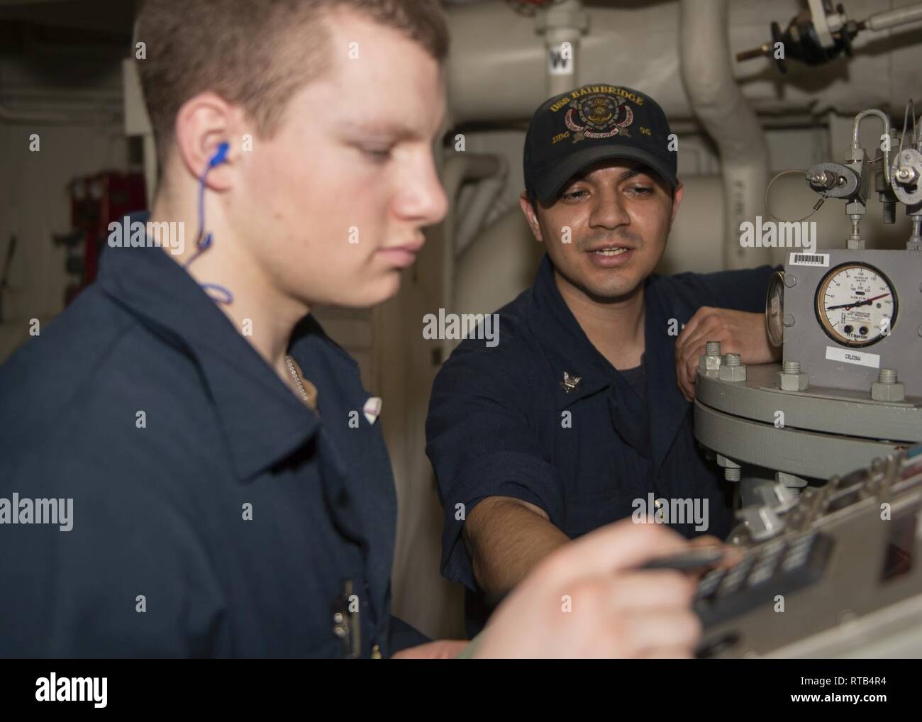 ATLANTIC OCEAN (Feb. 6, 2019) Gas Turbine Systems Technician (Mechanical) 2nd Class Caesar Garcia (right), from San Diego, Calif., provides training to Gas Turbine Systems Technician Fireman Jaxson Connell, from Bountiful, Utah, on how to operate a low-pressure air compressor (LPAC) in main engine room (MER) 1 aboard the Arleigh Burke-class guided-missile destroyer USS Bainbridge (DDG 96) during composite training unit exercise (COMPTUEX), Feb. 6. Bainbridge is currently underway conducting COMPTUEX with Carrier Strike Group (CSG) 12. The components of CSG 12 embody a “team-of-teams” concept,  Stock Photo
