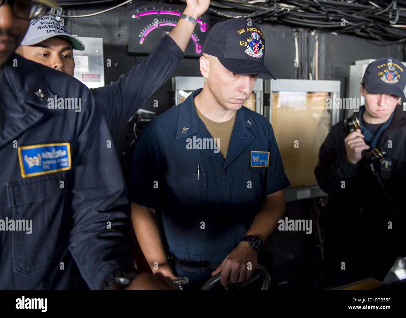 PACIFIC OCEAN (Feb. 7, 2019) Quartermaster 2nd Class Benjamin Channell, from Benton, Ark., assigned to the San Antonio-class amphibious transport dock ship USS Anchorage (LPD 23), stands master helmsman watch under instruction during an underway replenishment while on a deployment of the Essex Amphibious Ready Group (ARG) and 13th Marine Expeditionary Unit (MEU). The Essex ARG/13th MEU is a capable and lethal Navy-Marine Corps team deployed to the 7th fleet area of operations to support regional stability, reassure partners and allies and maintain a presence postured to respond to any crisis r Stock Photo