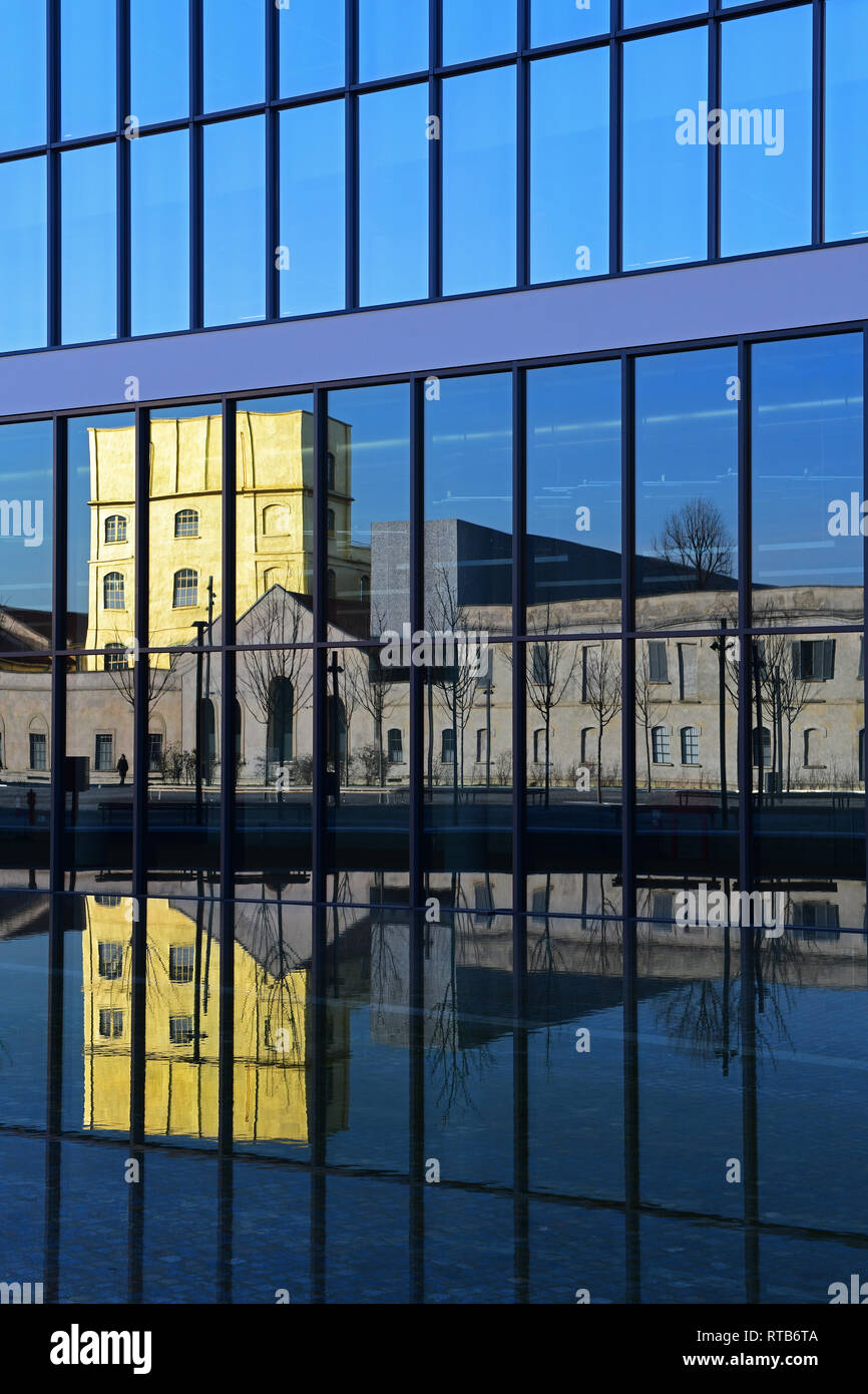 The Fondazione Prada buildings are reflected in a glass building of the recently finished piazza Adriano Olivetti,in the new Symbiosis district, Milan Stock Photo
