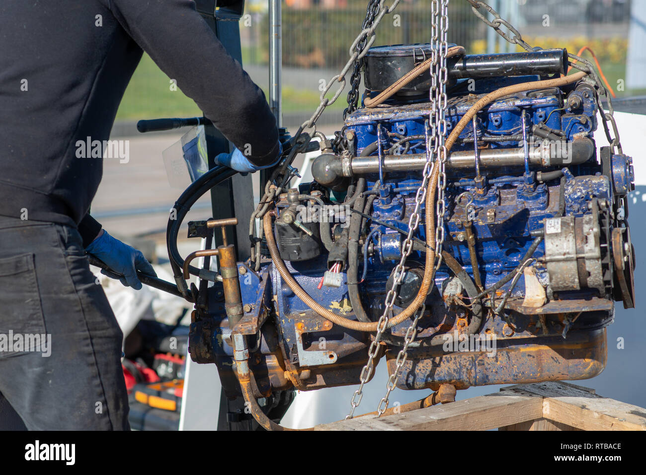 mechanic uses lifting equipment to remove engine block from boat Stock