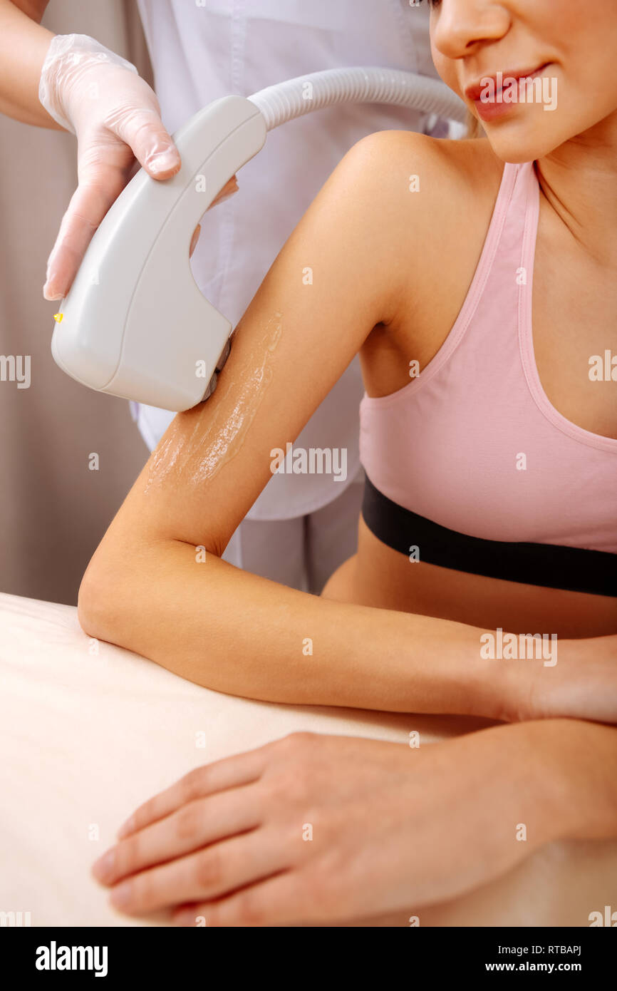 Woman wearing pink top having painless photo depilation of arm Stock Photo