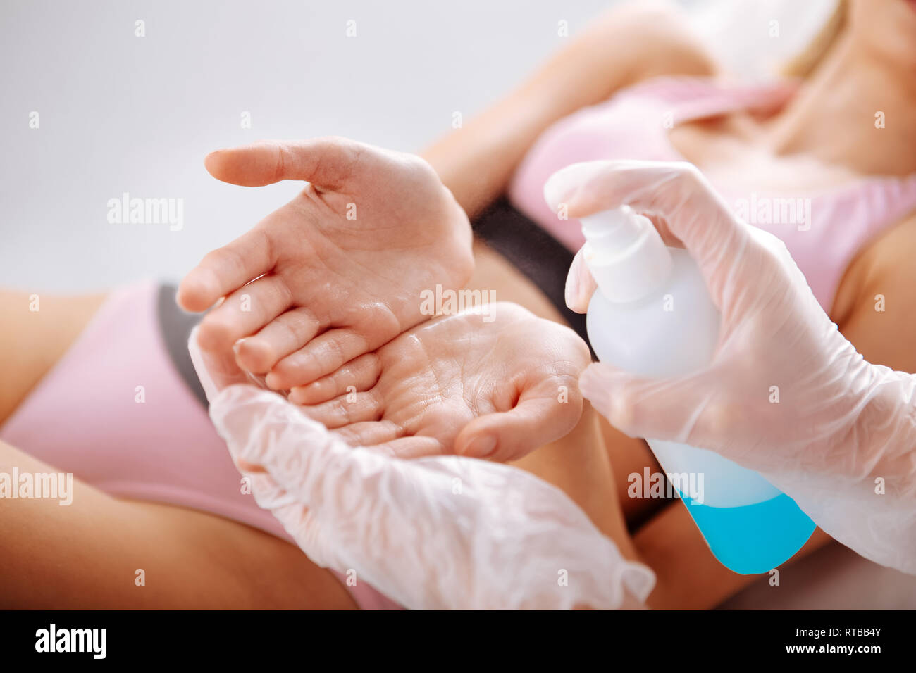 Specialist disinfecting hands of client before starting depilation Stock Photo