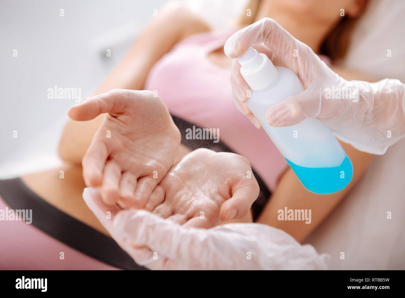 Young woman having hands disinfected before depilation Stock Photo