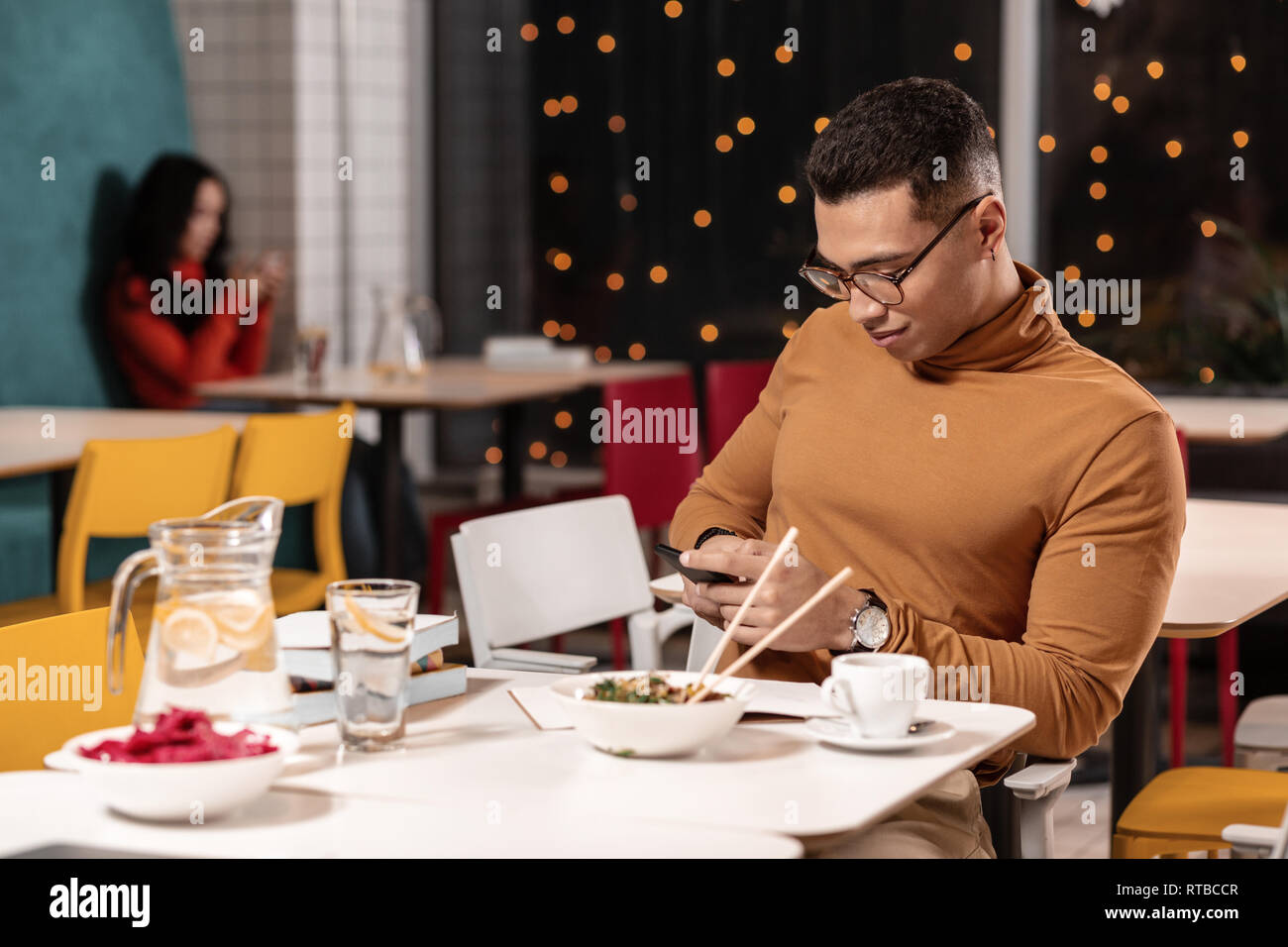 Man refusing to eat ordered dinner and chatting in the smartphone while sitting. Stock Photo