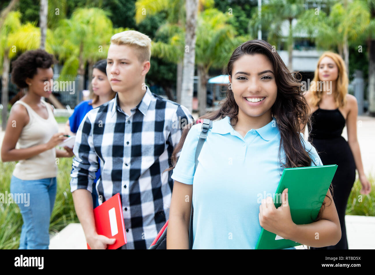 Latin american female student with caucasian and african teenage students outdoor in summer Stock Photo