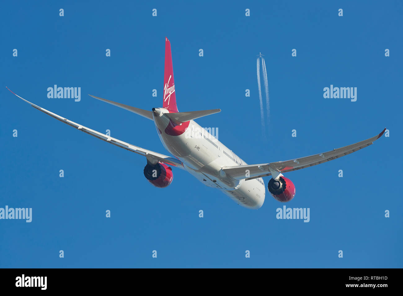 A Virgin Atlantic Boeing 787 Dreamliner Climbing Into Clear Blue Skies, A High Flying Boeing 747 Contrailing Overhead. Stock Photo