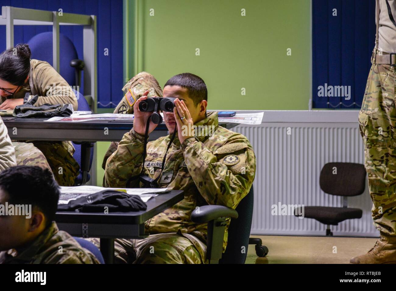 Sergeant Brian Arrango, assigned to First Squadron, Second Cavalry Regiment “War Eagles”, using his binoculars during a training session at the Call For Fire Trainer (CFFT) at Training Support Center. The CFFT provides a lightweight, rapidly deployable, observed fire training system that support all fire support missions. It is depicting current and future ammunitions and is expanded to train all soldiers regardless of MOS. Baumholder, Germany on February 09, 2019 Stock Photo