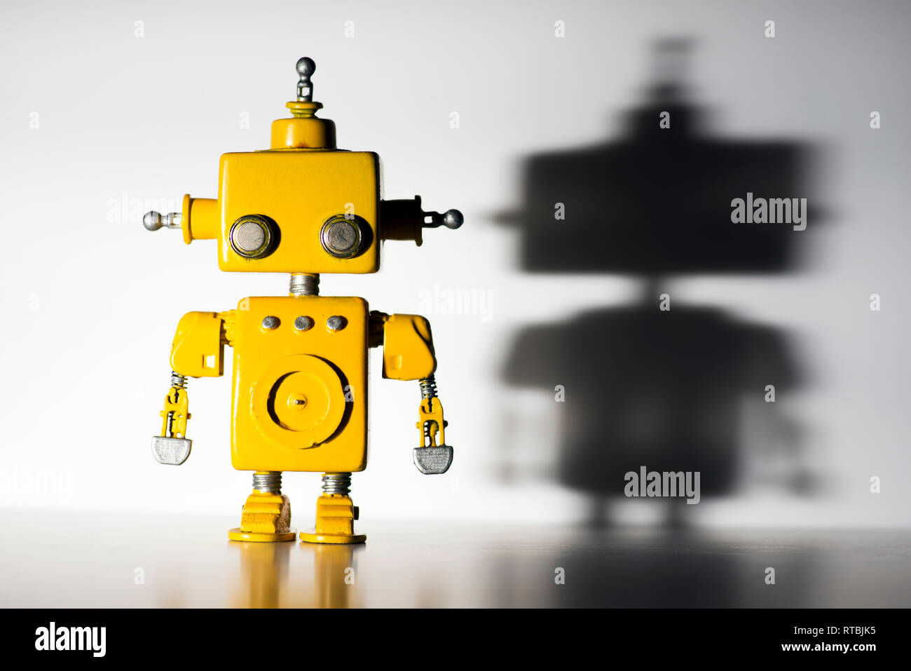 Cute, yellow, handmade robot on a white background with hard shadow ...