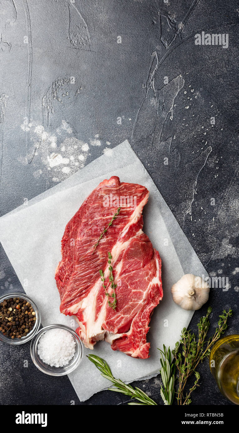 Fresh beef steak on black background with herbs and spices. Ready for cooking. Top view, down edge with copy space Stock Photo
