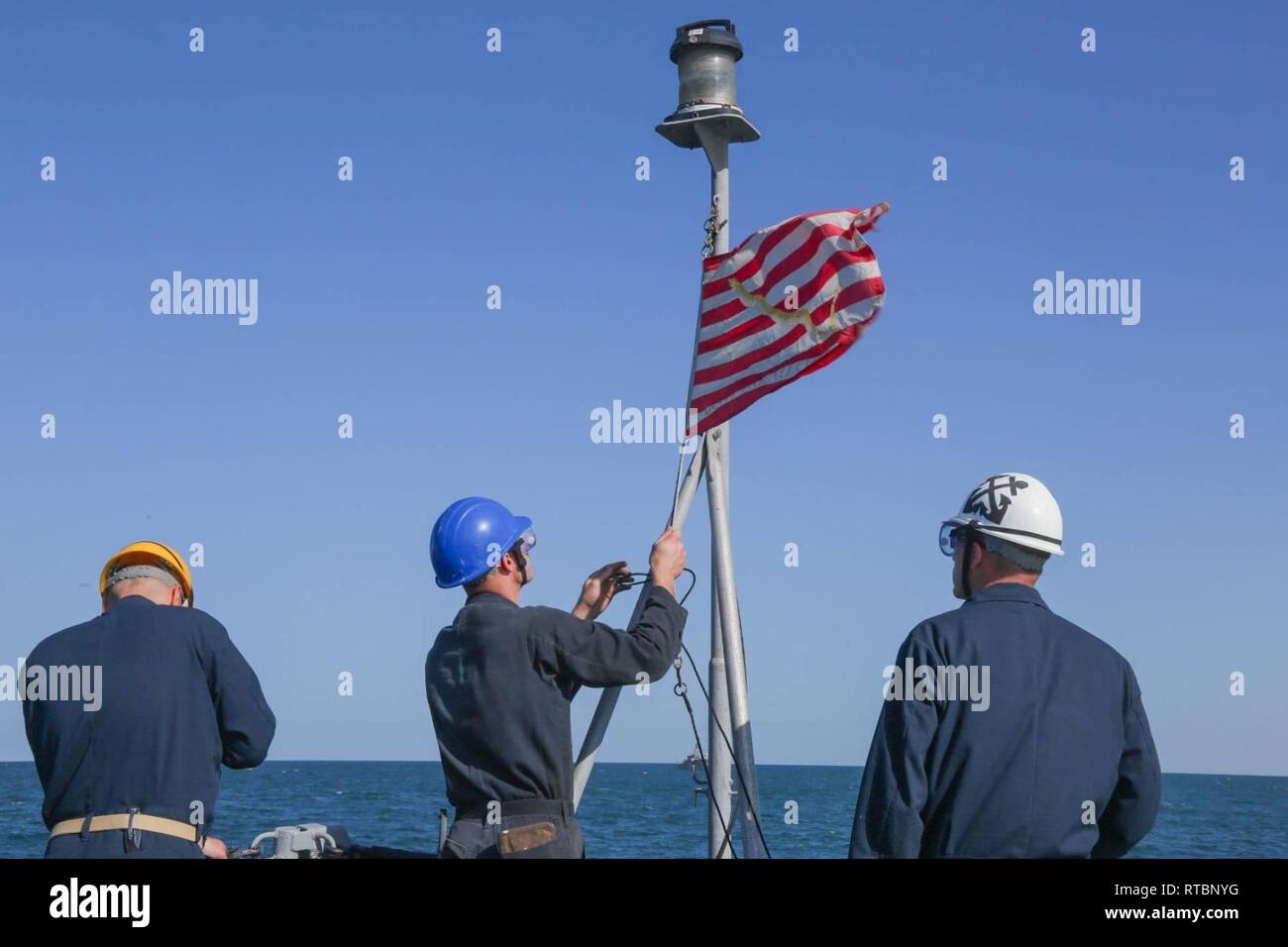 ARABIAN GULF (Feb. 9, 2019) Engineman 2nd Class John Vankouwenberg raises the Union Jack aboard the Cyclone-class coastal patrol ship USS Thunderbolt (PC 12). Thunderbolt is forward deployed to the U.S. 5th Fleet area of operations in support of naval operations to ensure maritime stability and security in the Central region, connecting the Mediterranean and the Pacific through the western Indian Ocean and three strategic choke points. Stock Photo