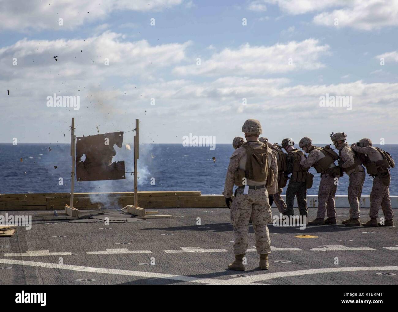 MEDITERRANEAN SEA (Feb. 11, 2019) - U.S. Marines assigned to the 22nd Marine Expeditionary Unit brace while a “donut charge” explodes during a live-fire breeching exercise on the flight deck of the San Antonio-class amphibious transport dock ship USS Arlington (LPD 24), Feb. 11, 2019. Arlington is making a scheduled deployment as part of the 22nd MEU and the Kearsarge Amphibious Ready Group, in support of maritime security operations, crisis response and theater security cooperation, while also providing a forward Naval and Marine presence. Stock Photo