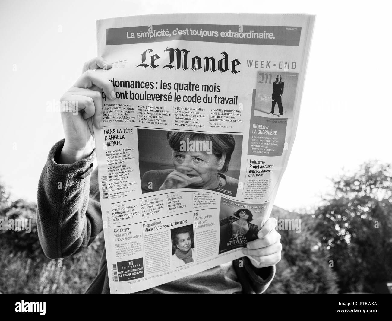 PARIS, FRANCE - SEP 24, 2017: View from below of woman reading latest newspaper Le Monde with portrait of Angela Merkel before the election in Germany for the Chancellor of Germany, the head of the federal government Stock Photo