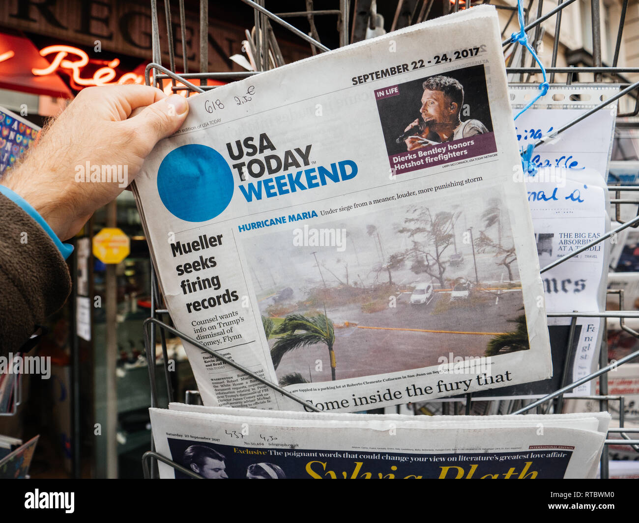 PARIS, FRANCE - SEP 23, 2017: Man buying latest newspaper USA TODAY with Hurricane Maria breaking news and picture of damages wind sea water  Stock Photo