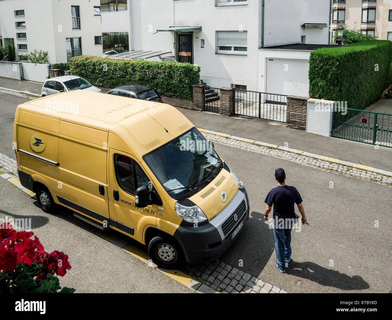 PARIS, FRANCE JUN 23, 2017 Courier walking toward La Poste yellow delivery van for the