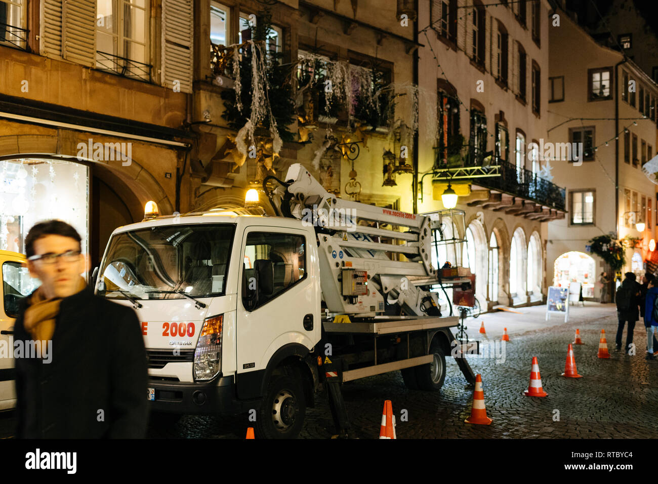 STRASBOURG, FRANCE - NOV 21, 2017: Decorating a shop facade for Christmas by using a truck with hydraulic ladder in central street with people at night  Stock Photo