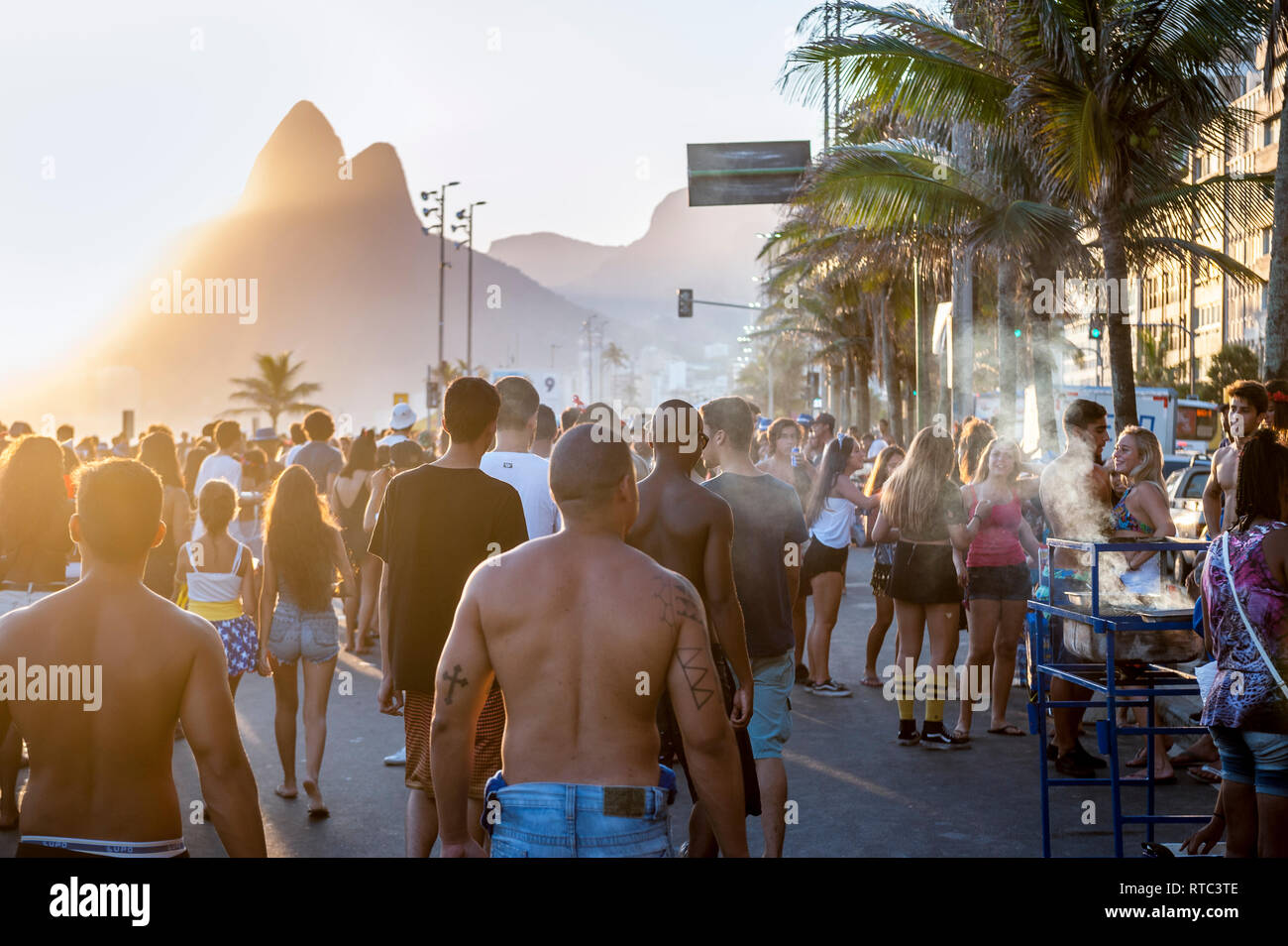 RIO DE JANEIRO - FEBRUARY 11, 2017: Crowds of Brazilians celebrate Carnival at a sunset bloco street party on the Ipanema beachfront. Stock Photo