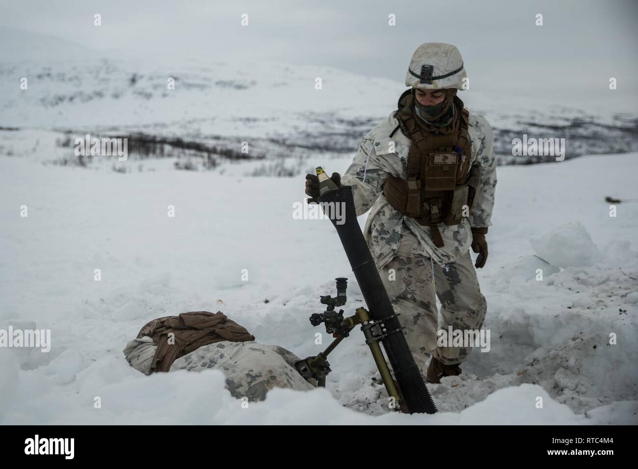 A U.S. Marine with Marine Rotational Force-Europe 19.1, Marine Forces Europe and Africa, drops a round in a M252 81 mm mortar system in Setermoen, Norway, Feb. 8, 2019. This training increased MRF-E Marines’ proficiency at cold-weather and mountain-warfare tactical operations in cold-weather environments. Stock Photo