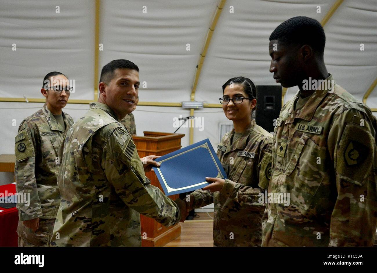 Capt. Diego Hernandez, Headquarters and Headquarters Company commander, Special Troops Battalion, 300th Sustainment Brigade, presents a certificate of achievement to Spc. Surachhya Neupane at Camp Arifjan, Kuwait, Feb. 8, 2019. Stock Photo
