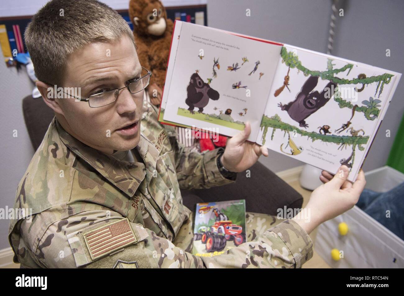 U.S. Air Force Capt. Nathan Badger, 34th Intelligence Squadron flight commander, records himself reading a book as part of United Service Organizations (USO) Qatar’s reading program Feb. 8, 2019, at Al Udeid Air Base, Qatar. The USO reading program allows service members to record themselves reading books to send back to their children. Program participants can write messages in the books and send them to their children along with the video recording. Stock Photo