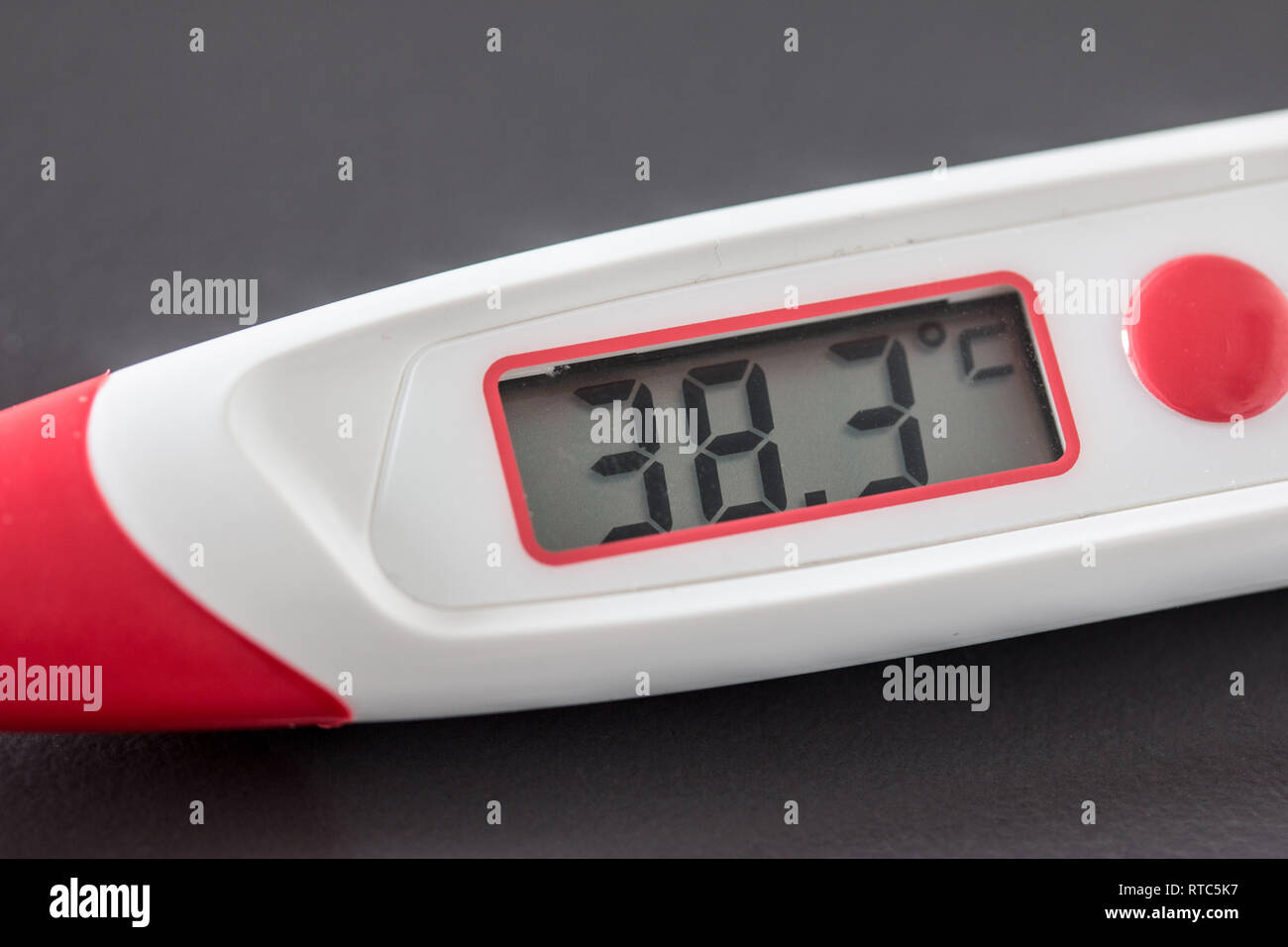 Red fever thermometer with digital display and 38 degrees Celsius lying on  the desk Stock Photo - Alamy