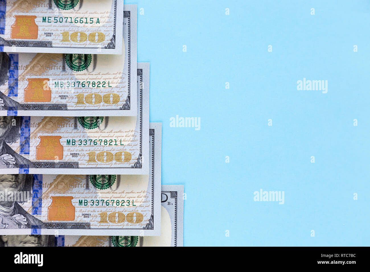 hundred dollar bills lie in the form of a ladder on a blue background with free space for text Stock Photo