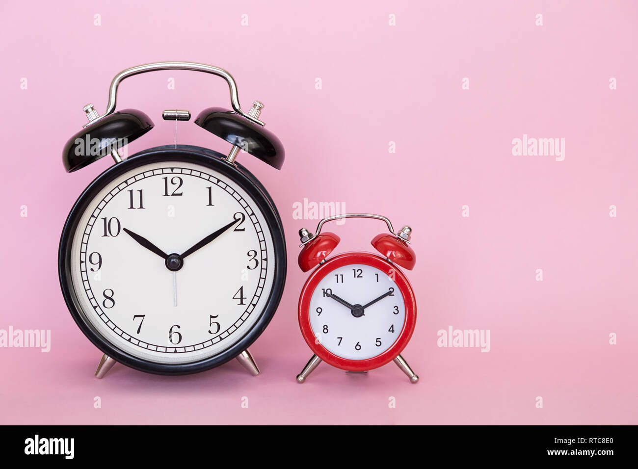 two red and black retro alarm clocks on a pink colored background with free space for text Stock Photo
