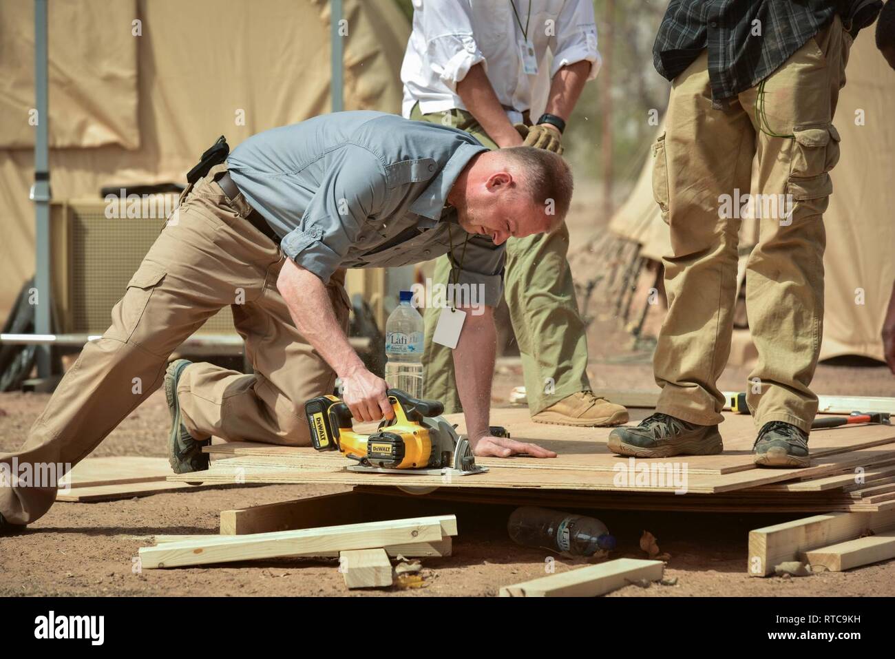 U.S. Army engineers saw wood to update tent layouts at the Flintlock camp in Loumbila, Burkina Faso during the pre-stages of Exercise Flintlock 2019 Feb. 12, 2019. Engineers like these were part of an advance team that arrived a week prior to everyone else to ensure each Flintlock outstation was built properly and met the requirements for an exercise of Flintlock's scale. Stock Photo