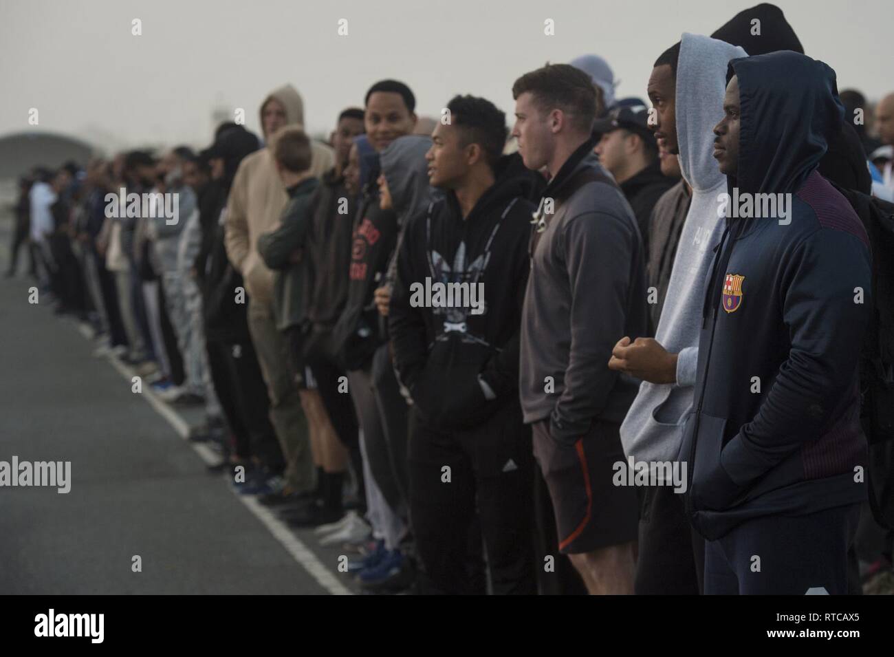 U.S., Qatar, and other coalition forces line up before a group run during Qatari National Sports Day Feb. 12, 2019, at Al Udeid Air Base, Qatar. U.S. and Qatar military forces were able to compete in team events including basketball, volleyball and soccer, as well as individual events such as swimming and ping pong throughout the morning. Qatari National Sports Day provided servicemembers from both nations an opportunity to strengthen military relations through friendly competition. Stock Photo