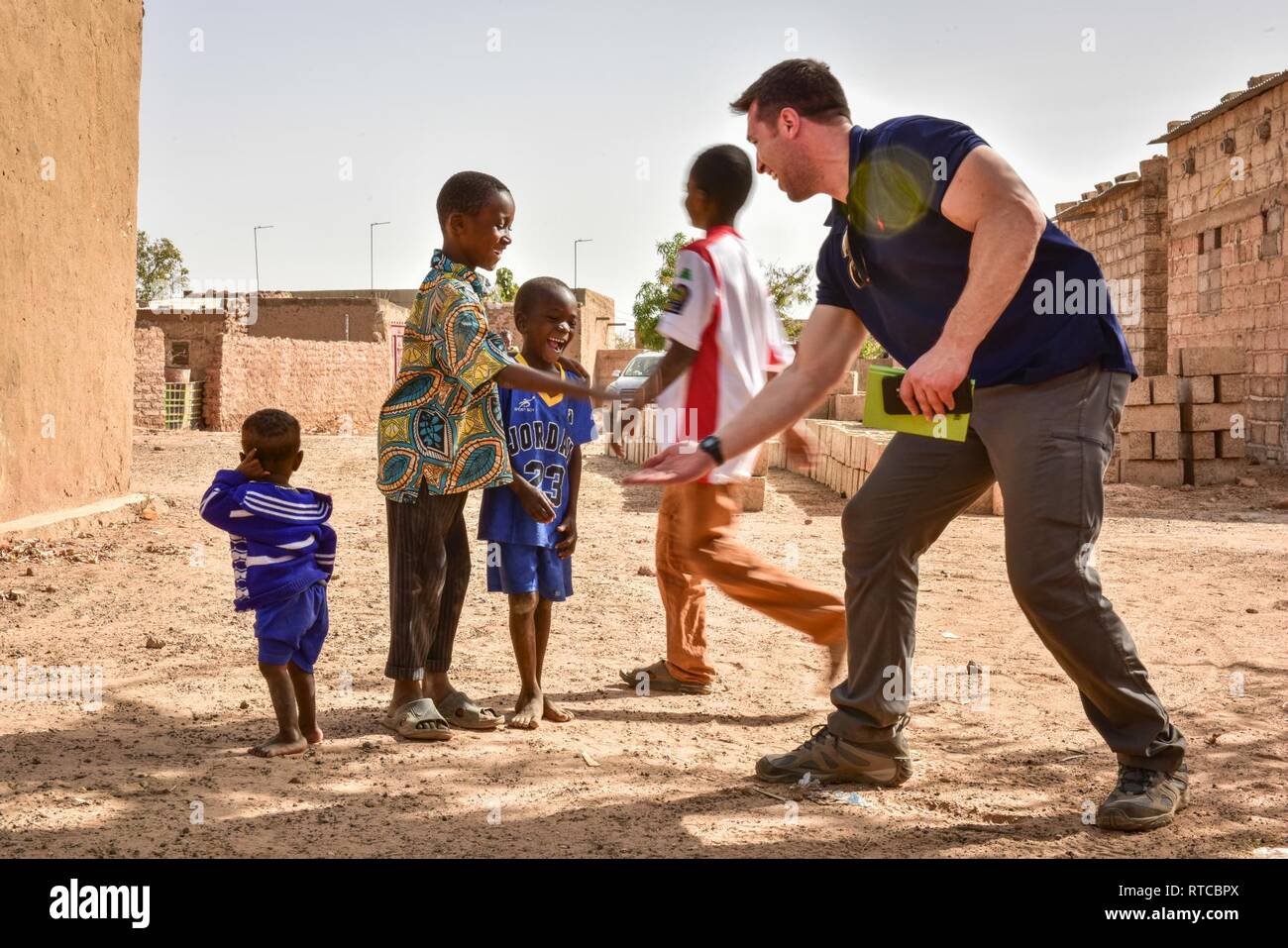 Local Burkinabe children give high fives with a U.S. Army Soldier assigned to the 122nd Civil Affairs Team during a site survey to evaluate a medical clinic in Loumbila, Burkina Faso, Feb. 13, 2019. Through key leader engagements, the Civil Affairs team works to further improve relations between the local national populous and U.S. forces during exercise Flintlock 2019. Stock Photo