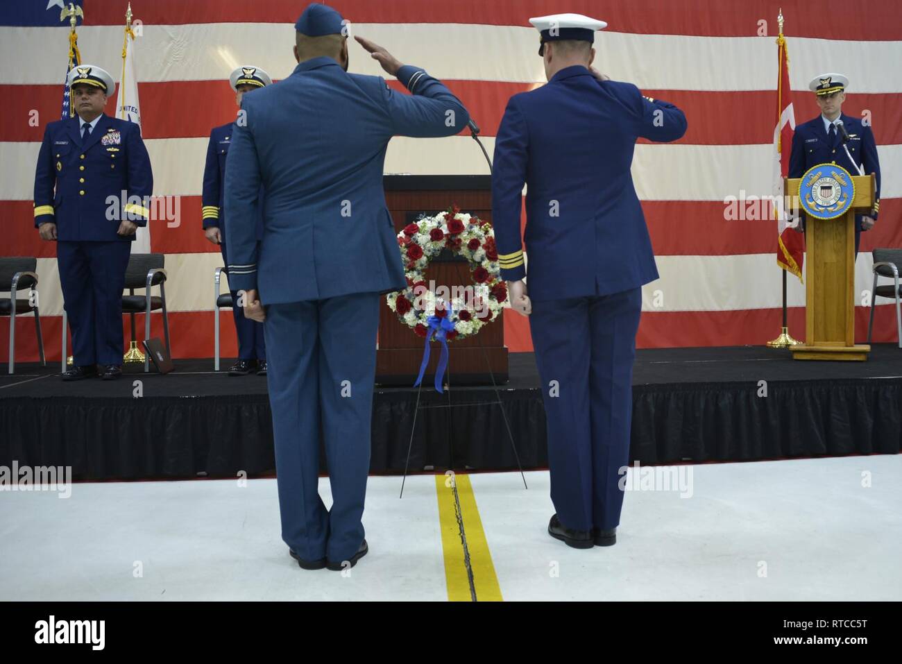U.S. Coast Guard Lt. Cmdr. John Filipowicz and Royal Canadian Air Force Capt. Pete Wright salute the memorial wreath honoring the 40th anniversary of the crew of Aircraft 1432 who gave the ultimate sacrifice, Wednesday, Feb. 13, 2019, Cape Cod, Massachusetts. Both pilots, one crewmember, and a corpsman lost their lives in the accident, while the flight mechanic survived and was rescued by the fishing vessel. Stock Photo