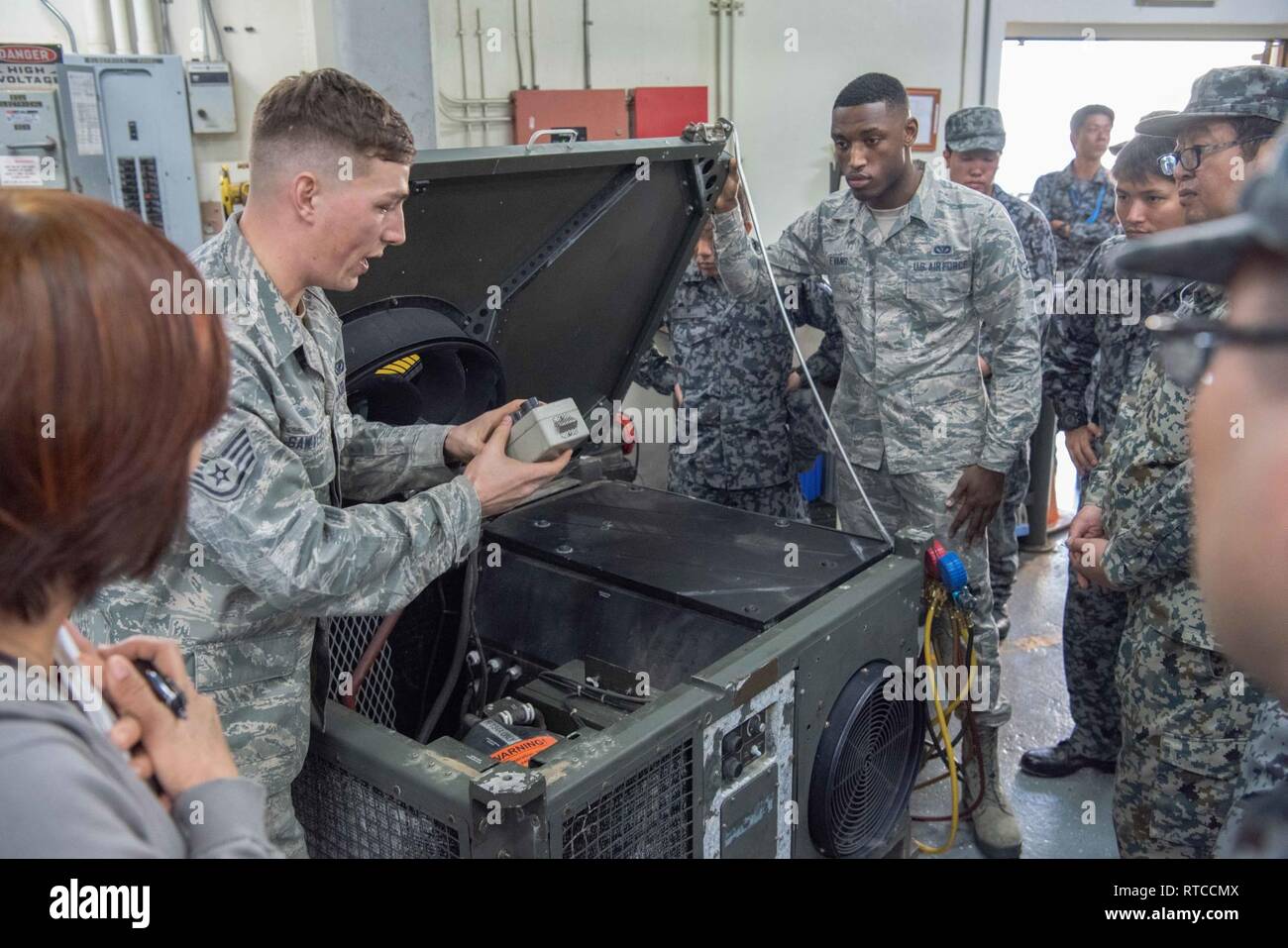 U.S. Air Force Airmen from the 18th Civil Engineer Squadron and members of  the Japan Air Self-Defense Force observe a heating, ventilation, and air  conditioning or HVAC unit during a formal training