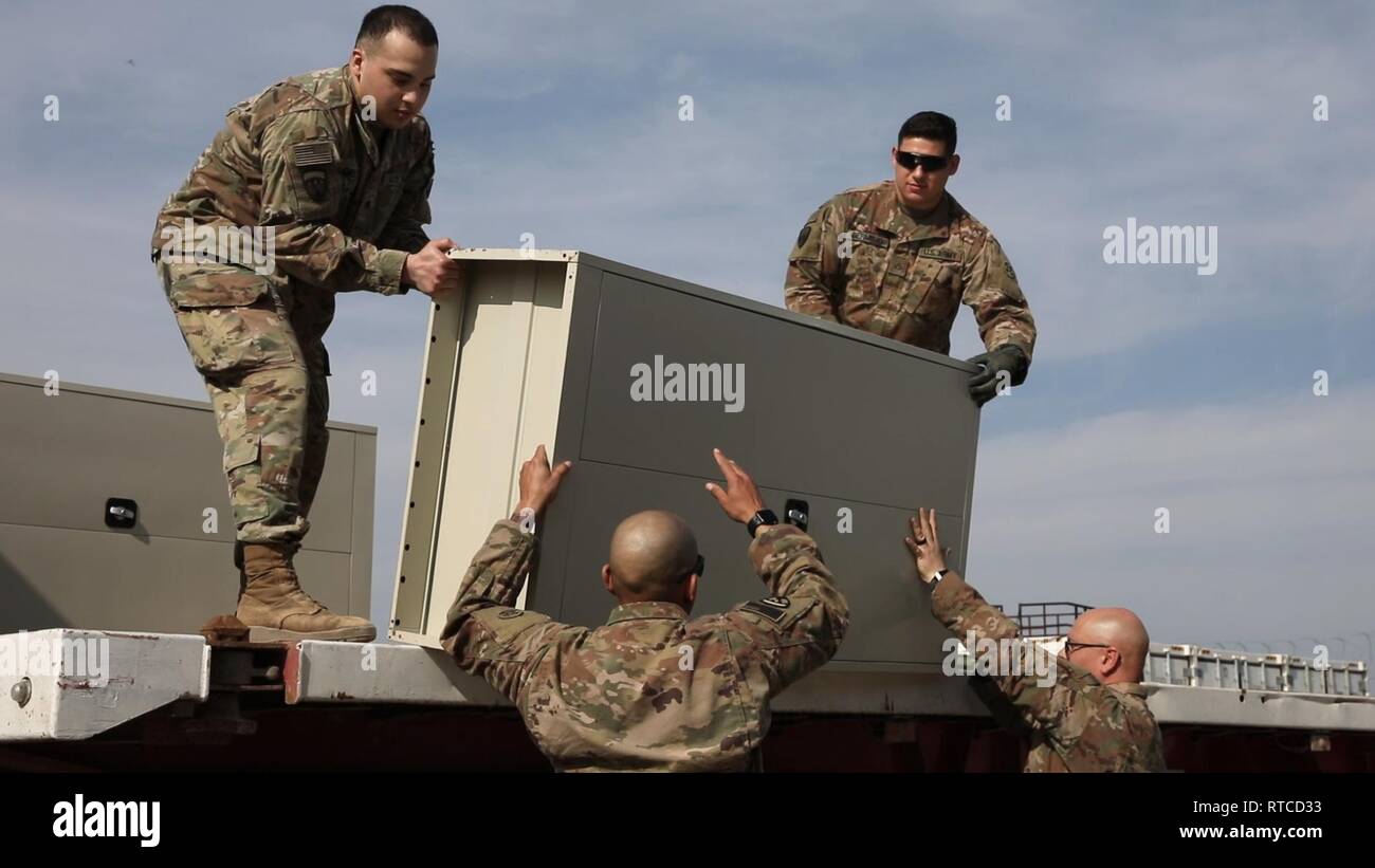 Staff Sgt. Richard Bowen, Staff Sgt. Radames Serrano, Spc. Eric Lopez and Pfc. Zachary Bermejo, 869th Movement Control Team, unload lockers and other equipment for the Iraqi Female Police Academy in a central receiving and shipping yard at the Baghdad Diplomatic Support Center Feb. 13, 2019.  Soldiers are allowed to remove their tops and hats as environmental conditions change while working in the yard . Stock Photo