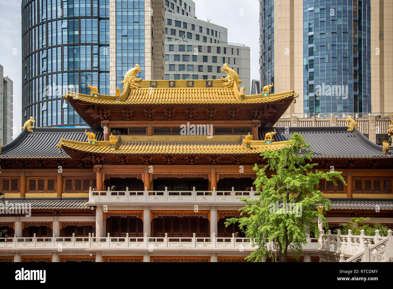 A traditional double eave ornate roof of Jing' An Temple or Temple of Peace and Tranquility juxtaposed with the sleek lines of the skyscrapers behind. Stock Photo