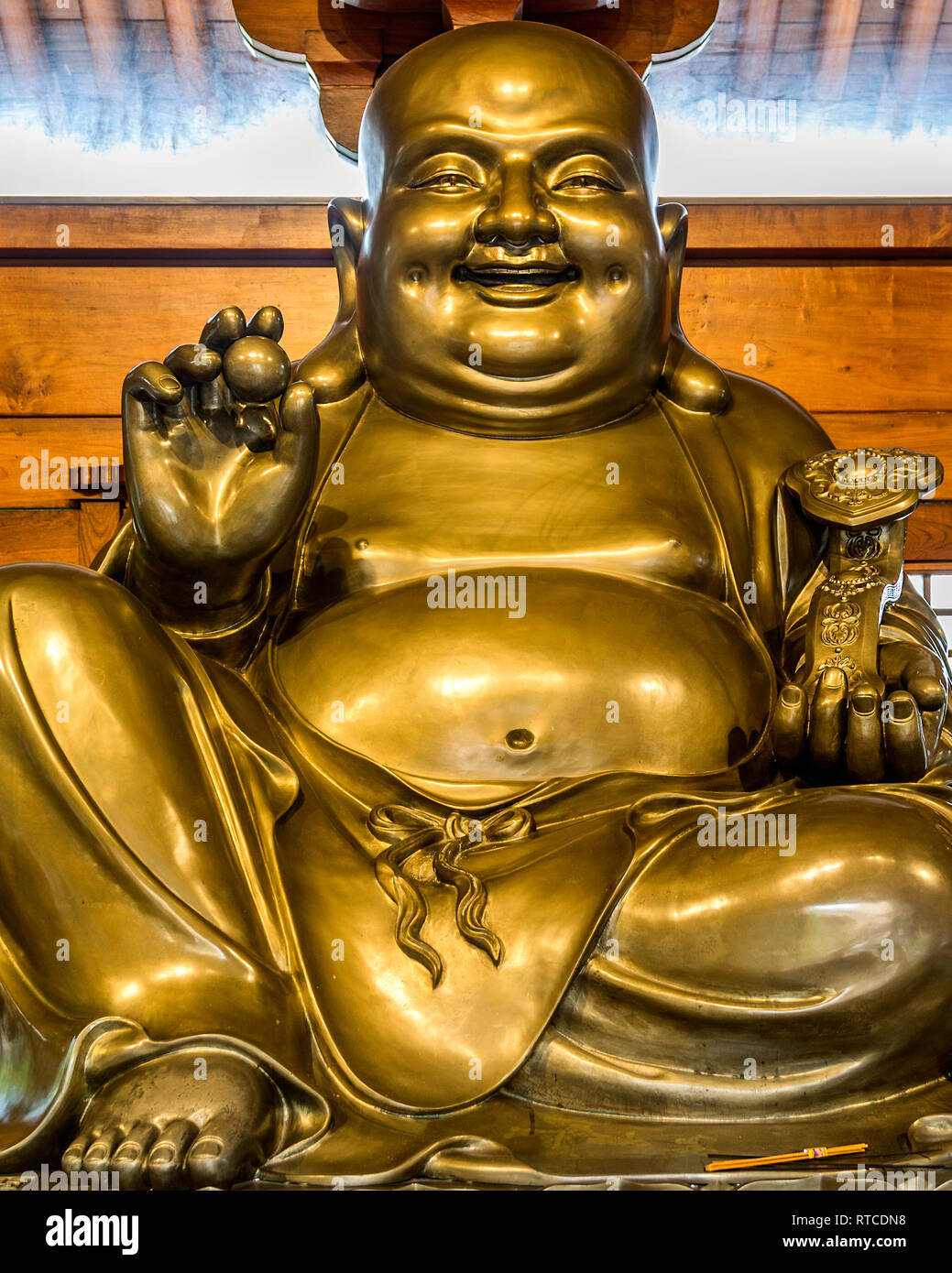 Buddha of abundance and happiness. A gold statue of a Laughing Buddha