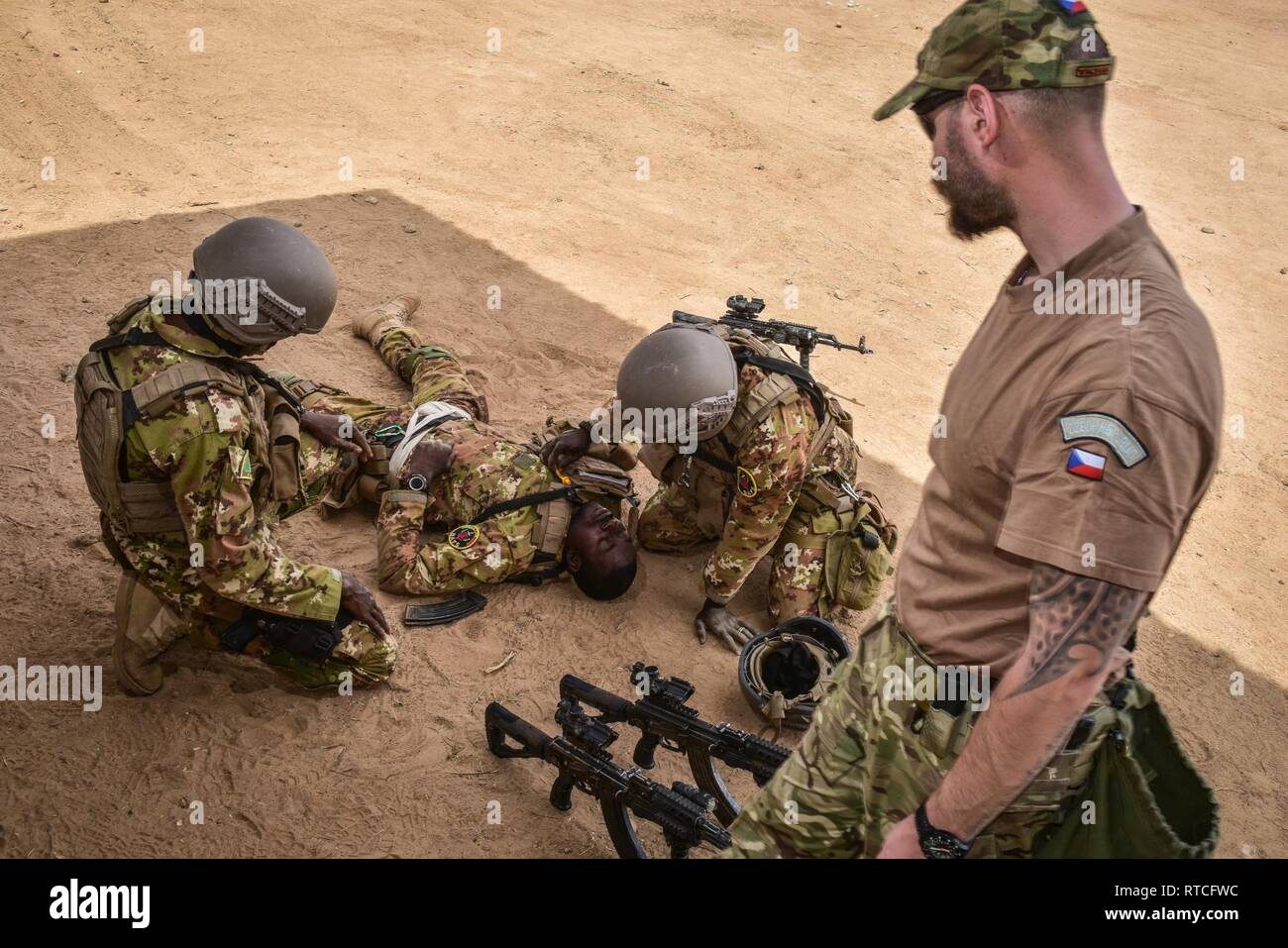 A Czech Special Forces Soldier observes Malian Soldiers as they tend to a simulated injured soldier during Flintlock 2019 medical training in Loumbila, Burkina Faso Feb. 16, 2019. The medical training provides Malian Soldiers the opportunity to get hands on medical experience from multinational special forces soldiers. Stock Photo