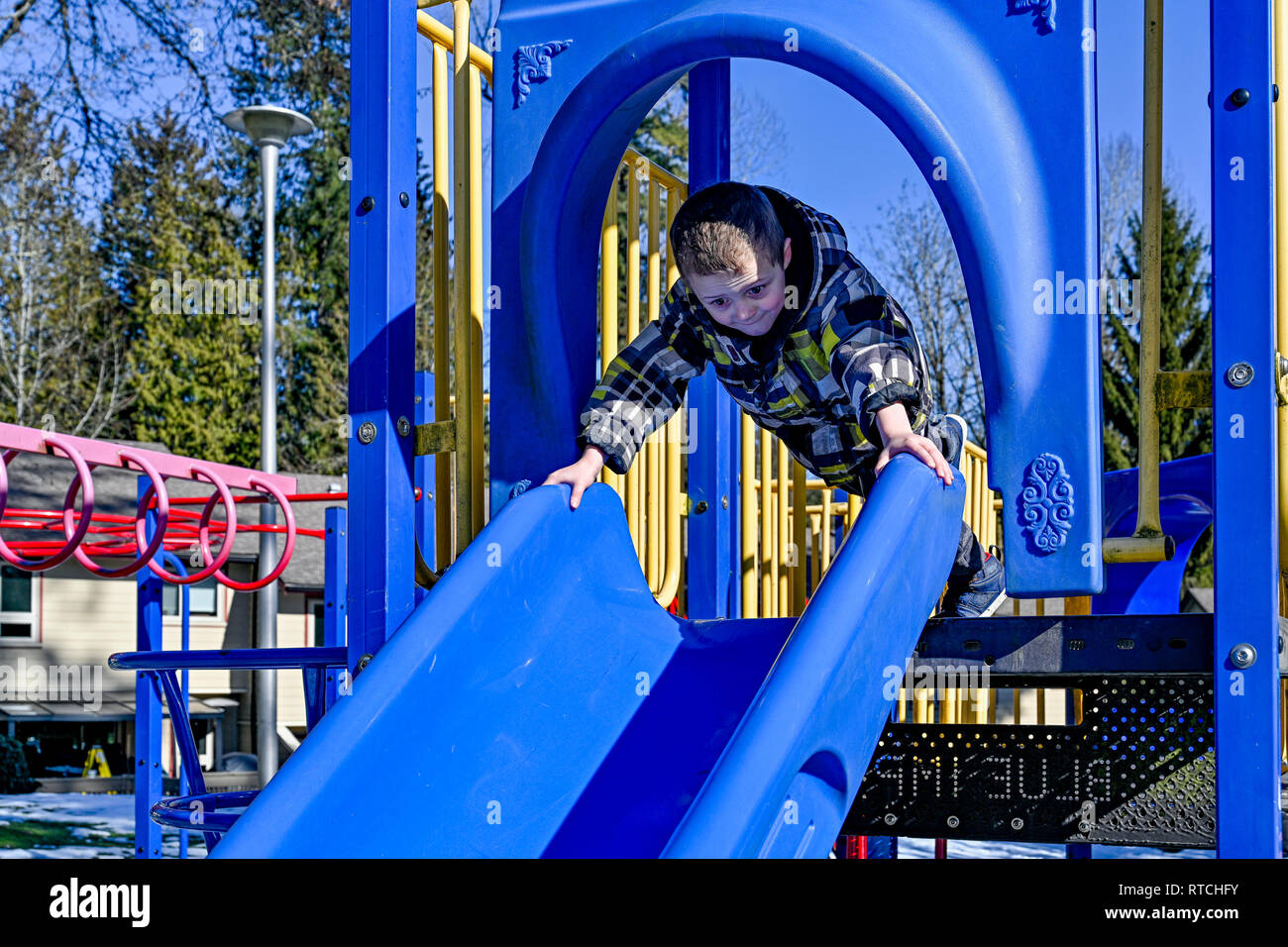 Young boy on playground slide Stock Photo