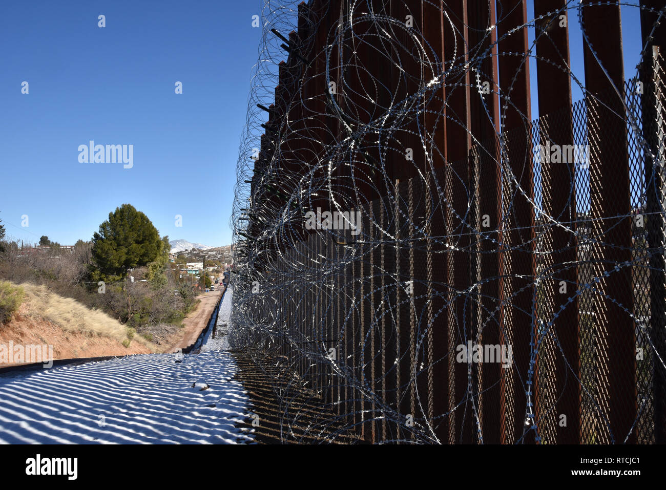 Four rows of concertina wire cover the metal wall in Nogales, Arizona, USA, at the international border with Nogales, Sonora, Mexico. Stock Photo