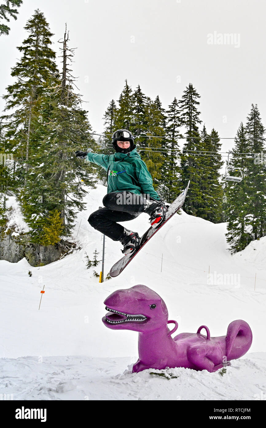 Young boy makes snowboarding jump over purple dinosaur at Mount Seymour