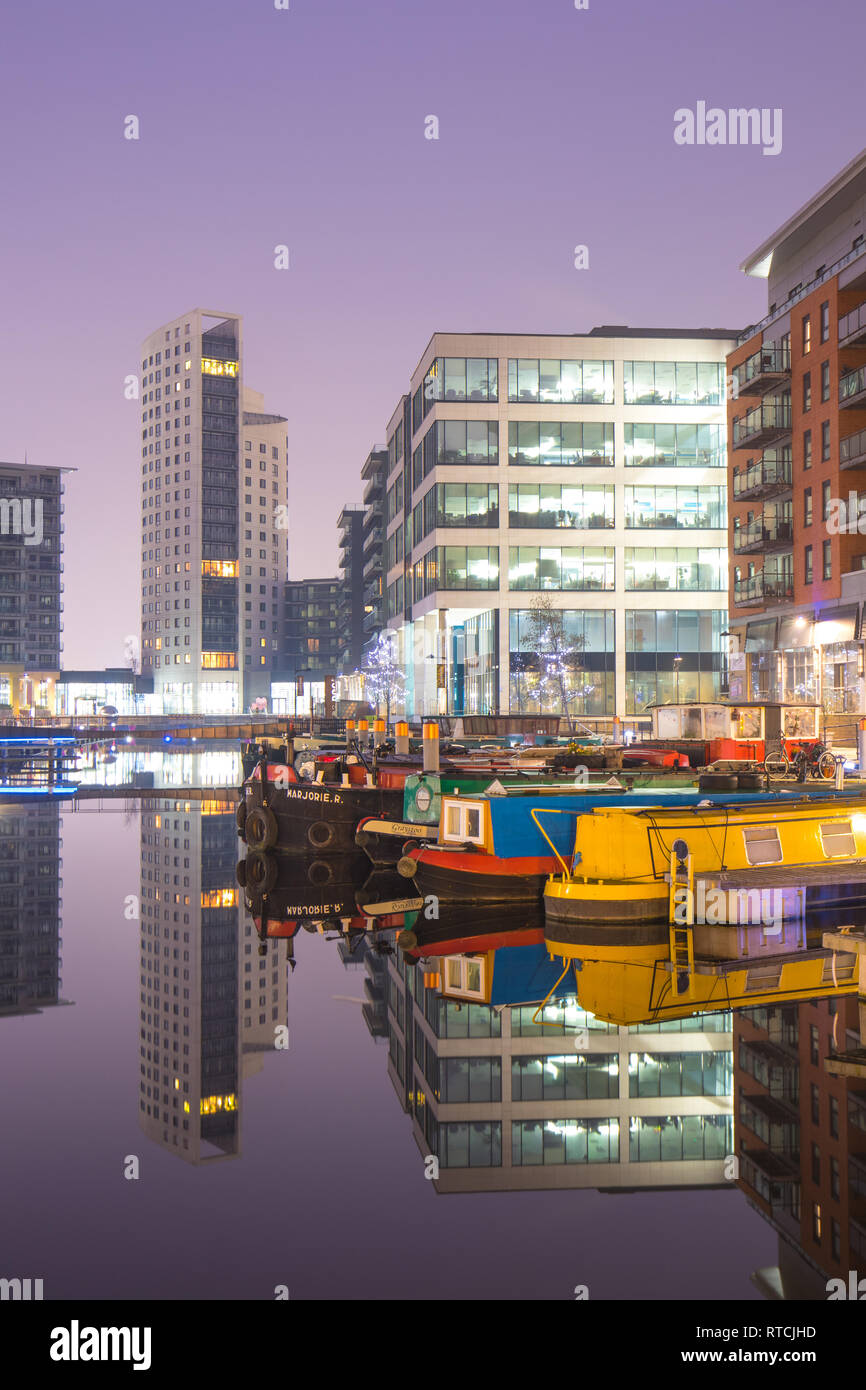 Reflections of moored narrowboats and apartments at Leeds Dock Stock