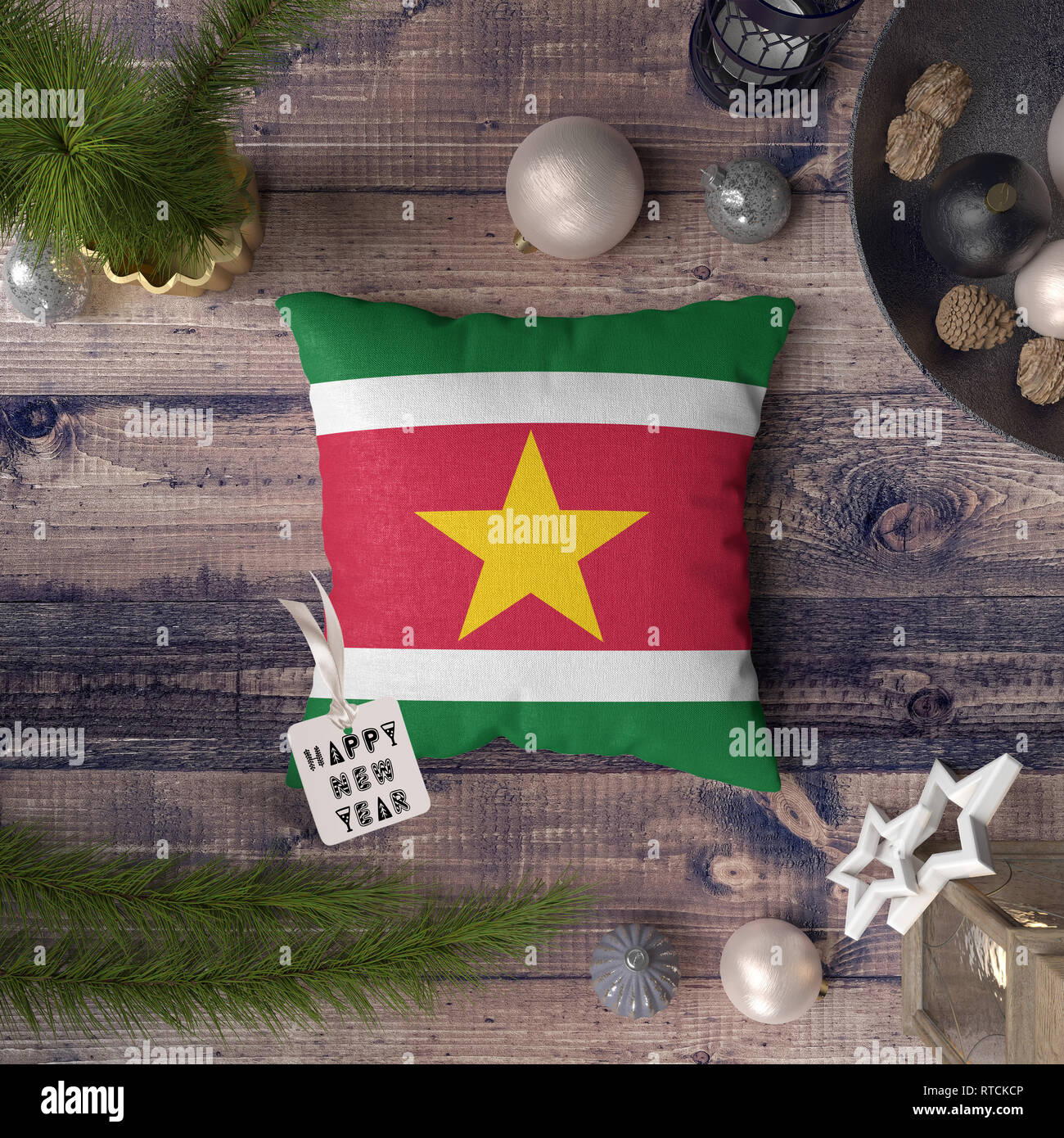 Happy New Year tag with Suriname flag on pillow. Christmas decoration concept on wooden table with lovely objects. Stock Photo