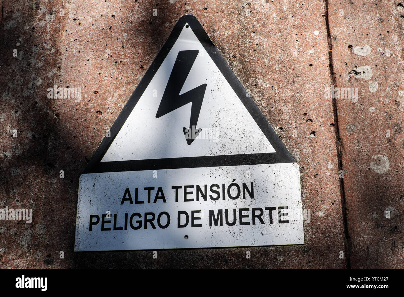 Electrocution sign warning of the danger of electrocution.Spanish text 'High voltage Risk of death' Stock Photo