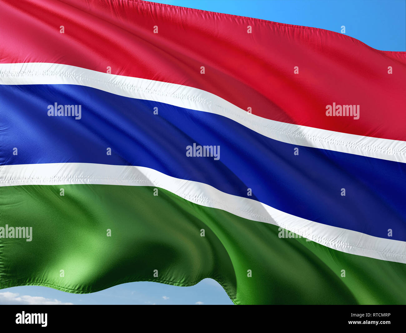 Flag of The Gambia waving in the wind against deep blue sky. High ...
