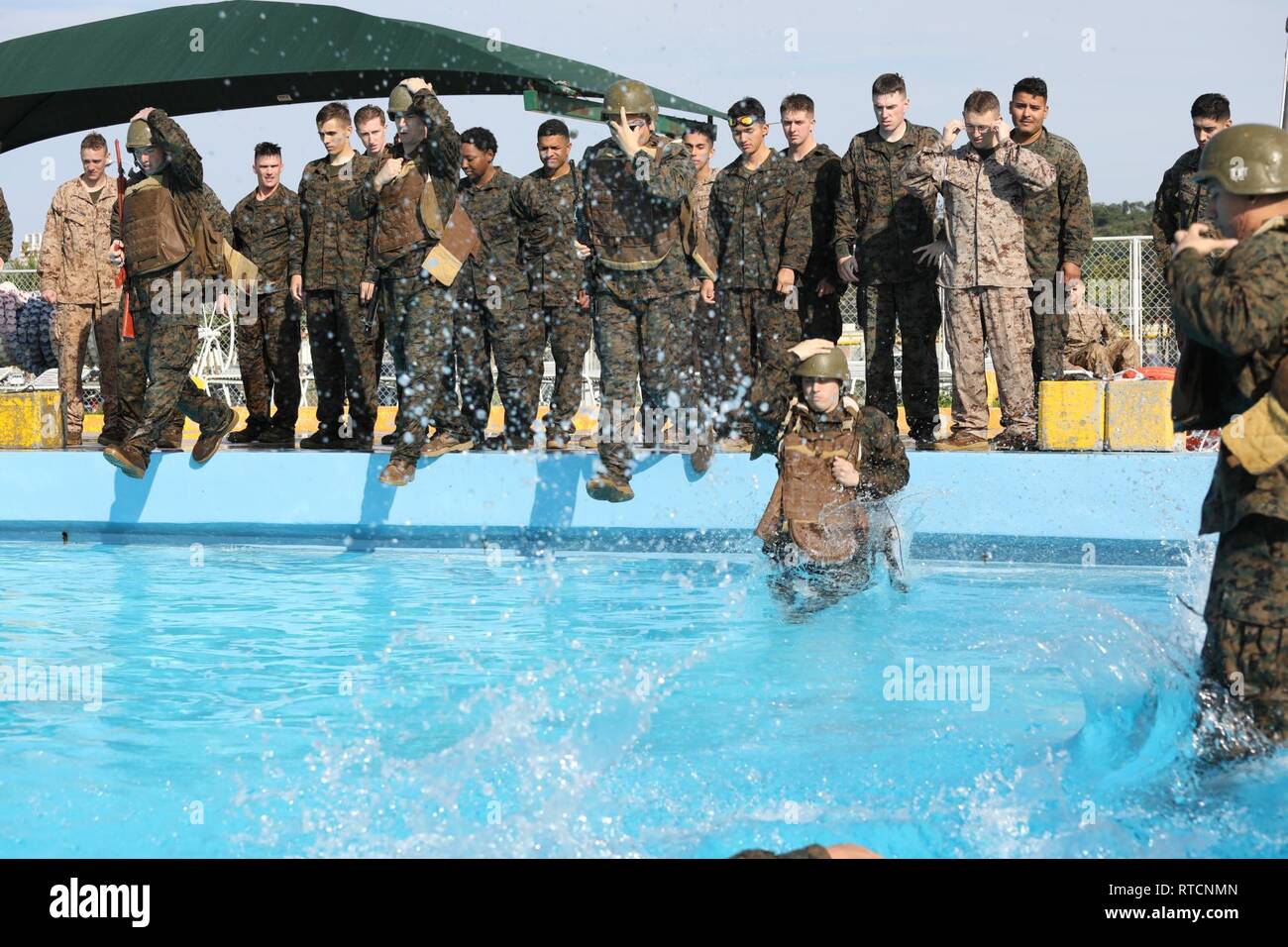 Marines jump into deep water and shed gear during an intermediate swim qualification on Camp Foster, Okinawa, Japan Feb. 14, 2019. Marines regularly complete their swim qualification to remain deployable and maintain overall unit readiness and fitness. Marines from 3rd Marine Logistics Group joined units from 3rd Marine Division and Marine Corps Installations Pacific to complete the training. Stock Photo