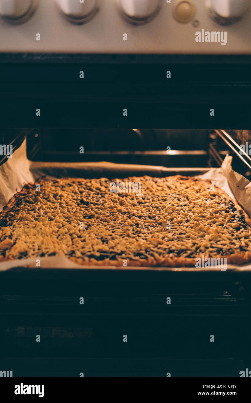 Cooked hot grated pie in open oven on baking tray, close-up. Freshly baked homemade cake comes from stove. Stock Photo