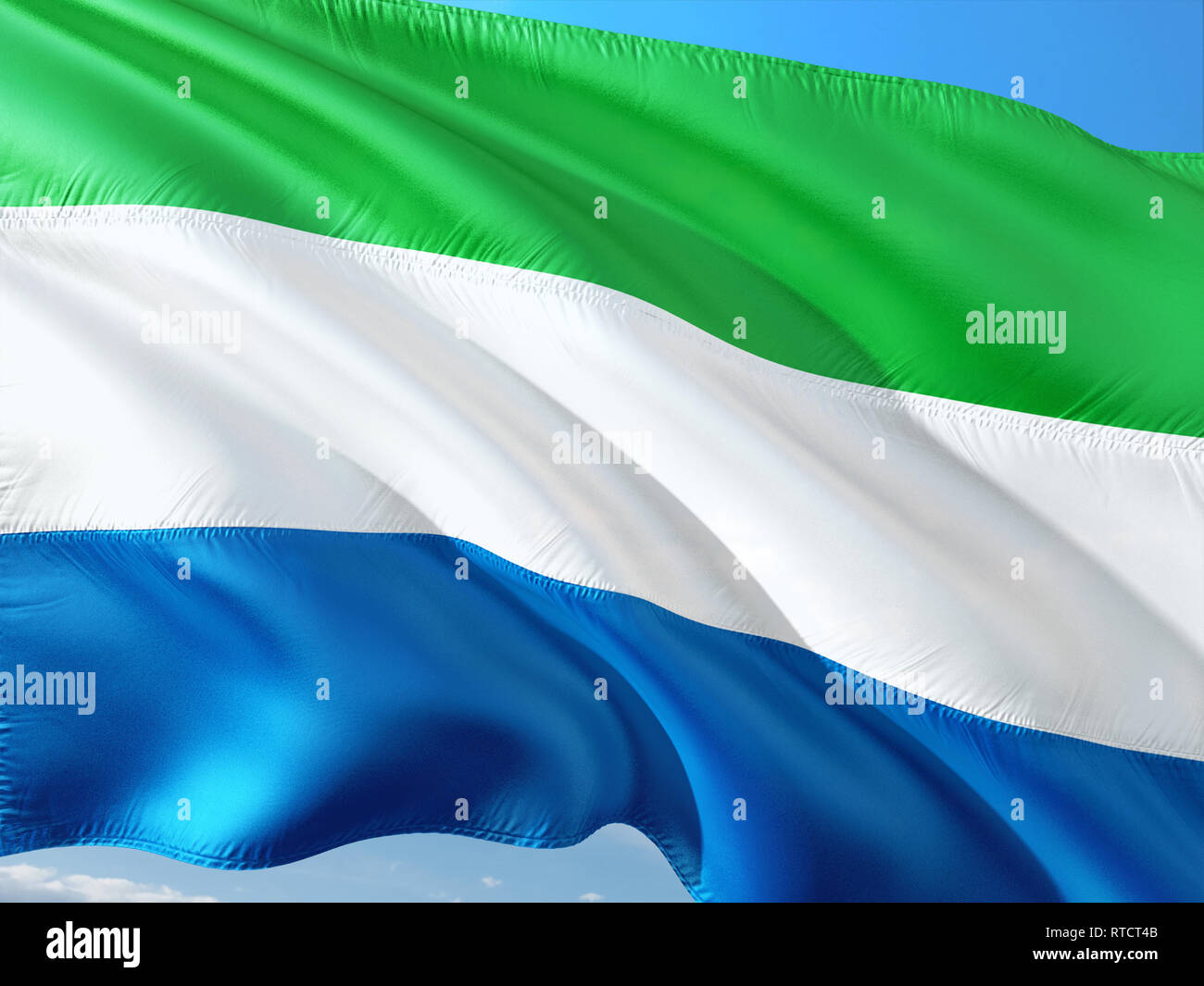 Flag of Sierra Leone waving in the wind against deep blue sky. High ...