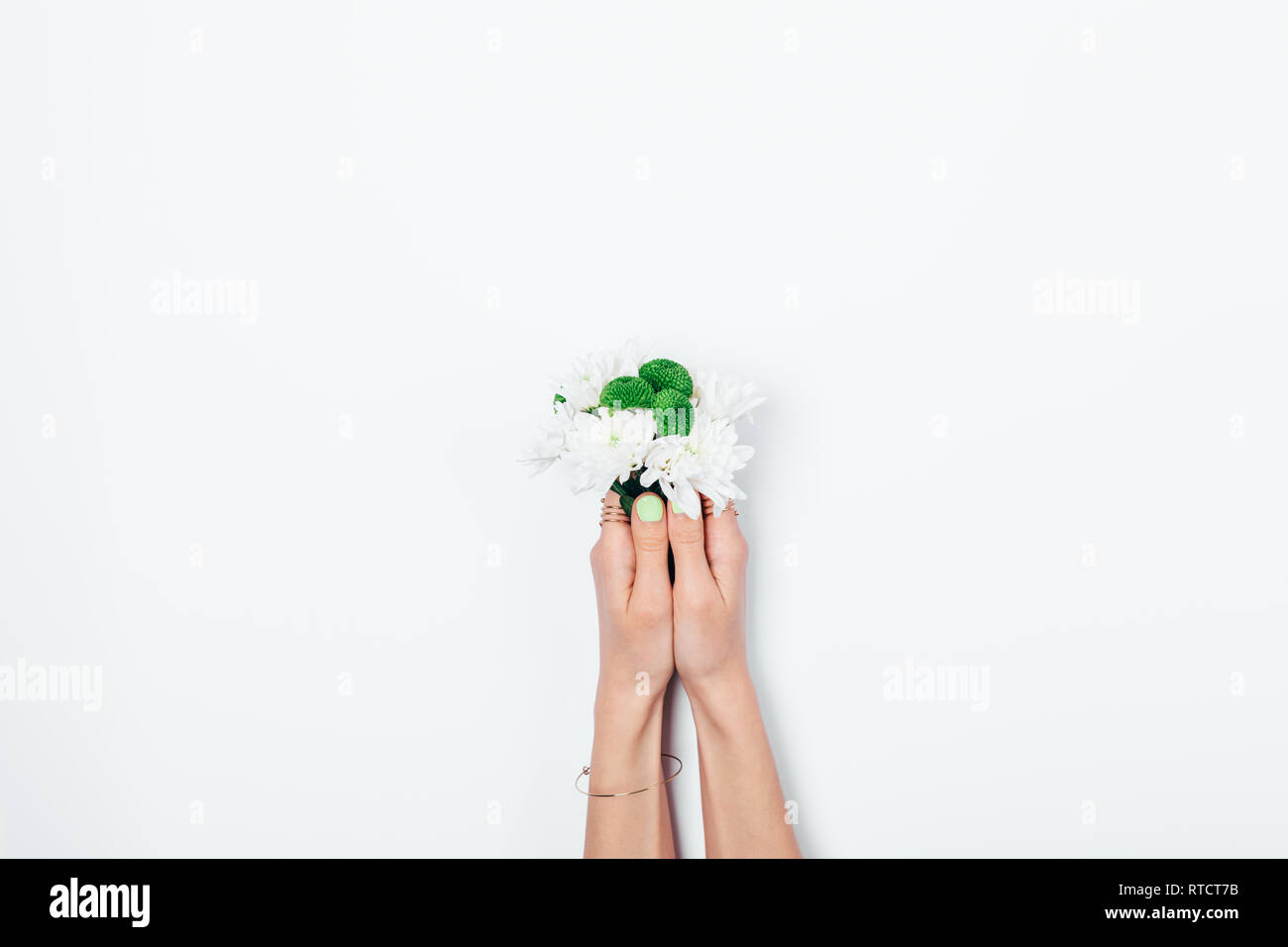 Small bouquet in female's hands with green manicure on white background. Woman holding fresh flowers. Stock Photo