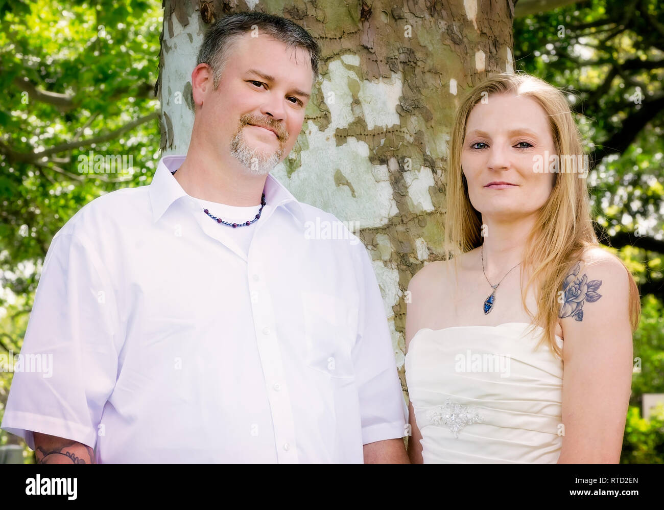 A young Caucasian couple poses for portraits after their wedding at Marshall Park in Ocean Springs, Mississippi. Stock Photo
