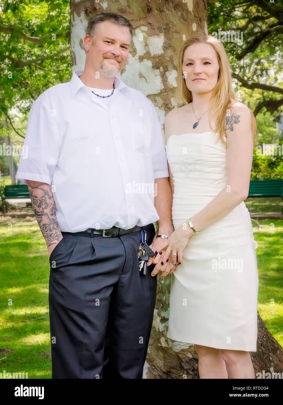 A young Caucasian couple poses for portraits after their wedding at Marshall Park in Ocean Springs, Mississippi. Stock Photo