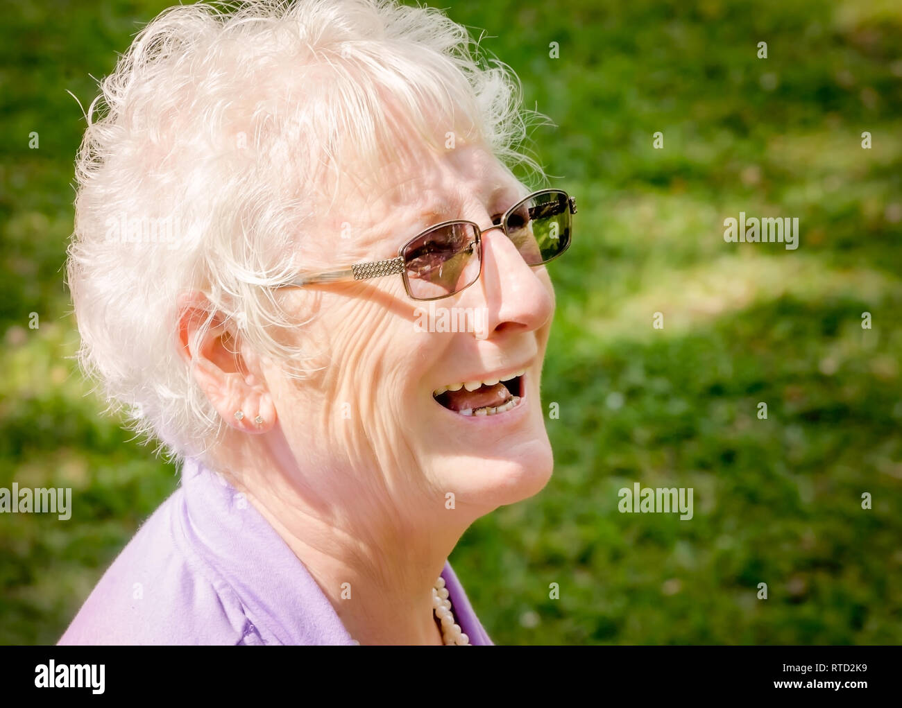 A mature woman wearing glasses smiles as she watches her daughter getting married at Marshall Park in Ocean Springs, Mississippi. Stock Photo