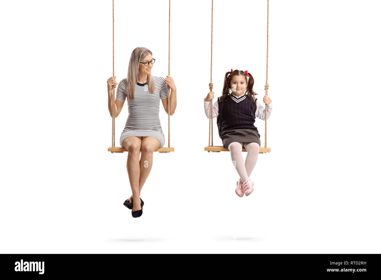 Full length portrait of a young woman and little schoolgirl sitting on swing isolated on white background Stock Photo